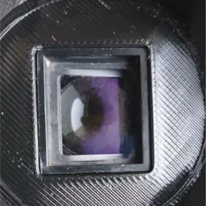 Close-up of a camera lens barrel showing a rectangular window with purple-tinted glass inside the mount area.
