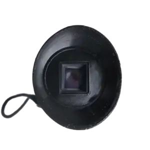 Close-up of a black camera lens with a square sensor window at the center and a circular outer ring, against a dark background.