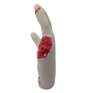 Close-up of a pale silicone prosthetic finger with fake blood and an open wound at the knuckle area for a Halloween/special effects prop