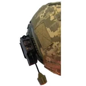 Close-up of a desert camouflage military helmet with a side rail and mounted equipment nearby the edge of the image.